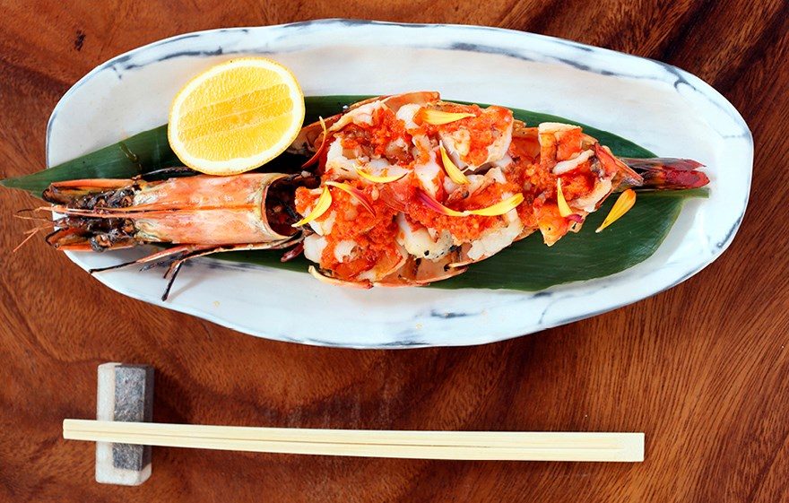 Grilled prawn and crayfish served on a long ceramic plate with lemon