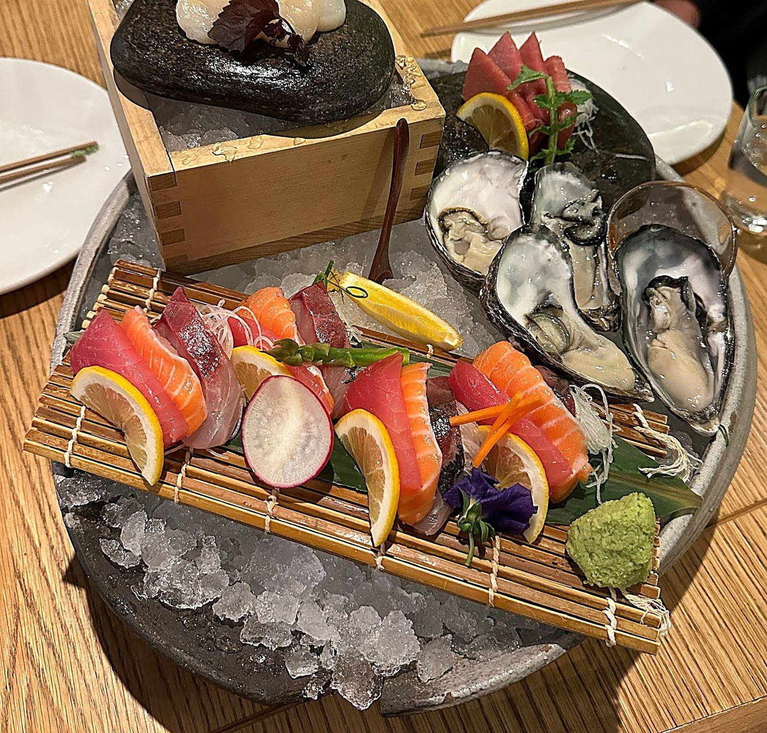 Sashimi and freshly shucked oysters on crushed ice, with a scallop served on a hot stone