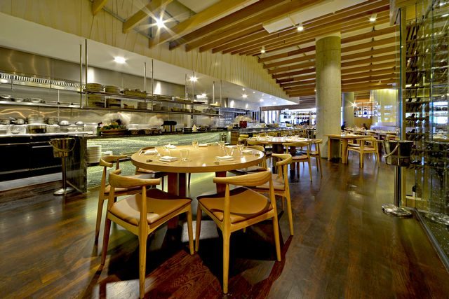 The dining room in daylight, with timber tables and the sushi counter