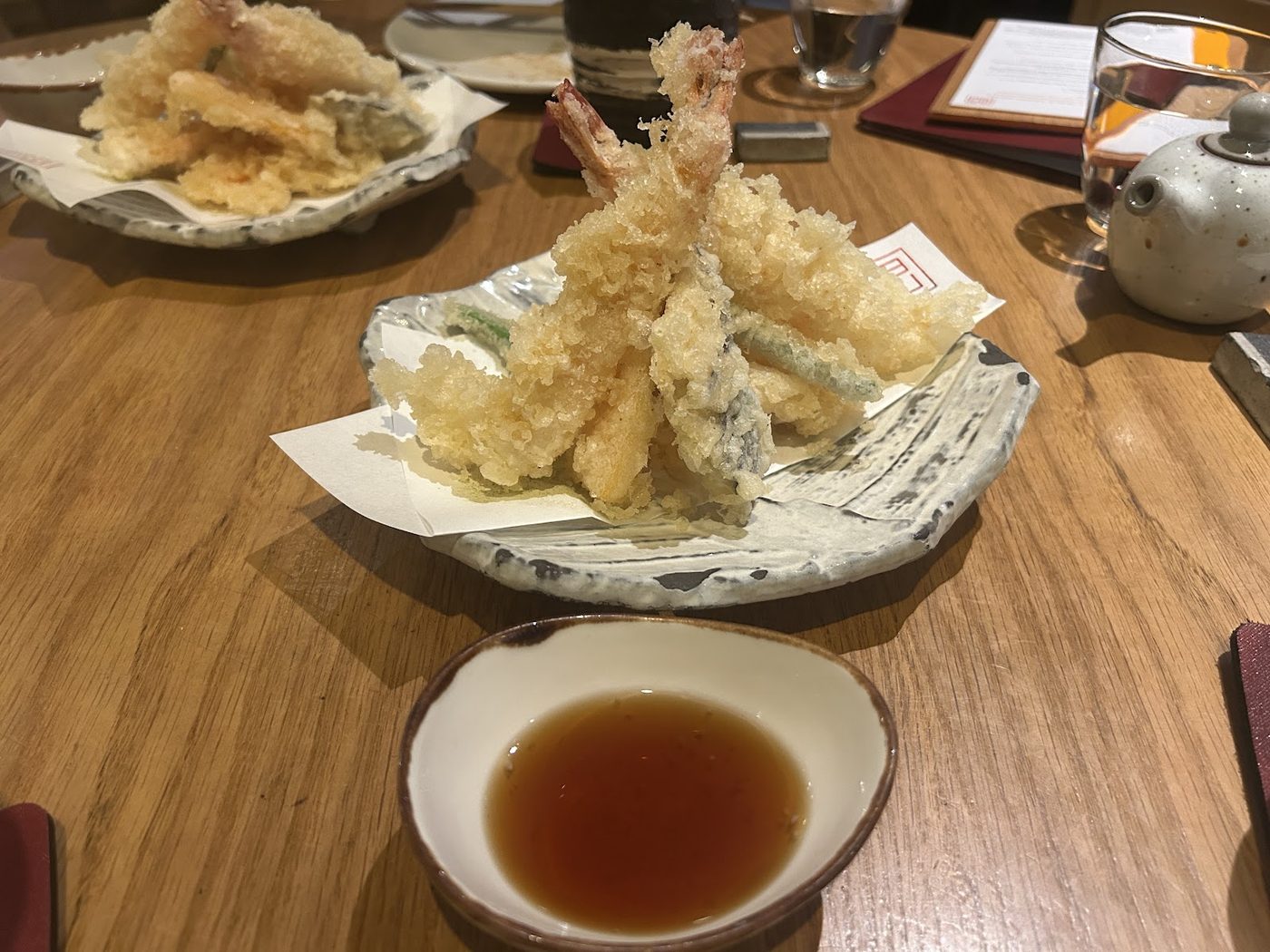 Tempura prawns and vegetables on paper-lined plates with dipping sauce